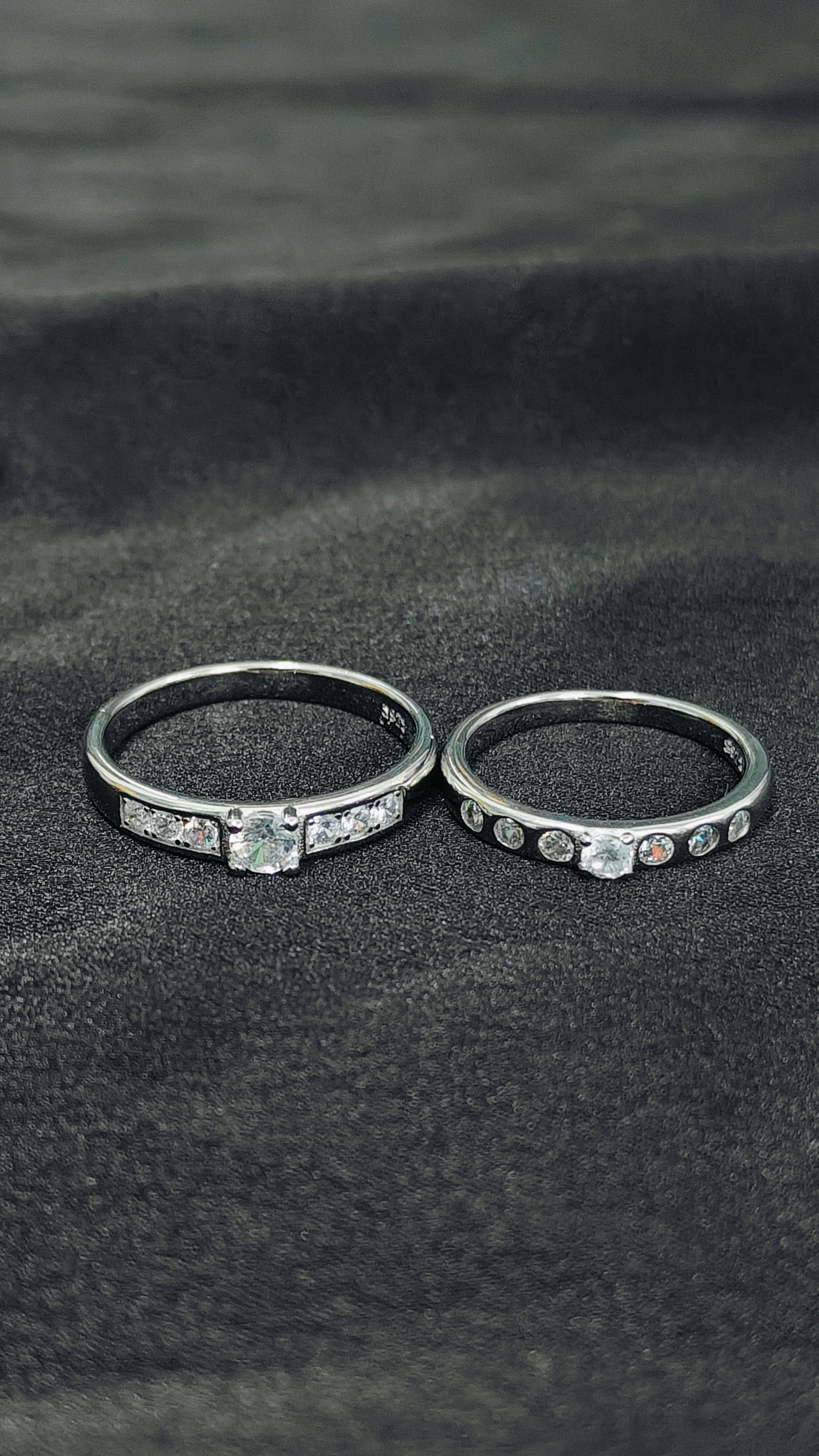 Two silver rings with gemstones on a dark fabric background