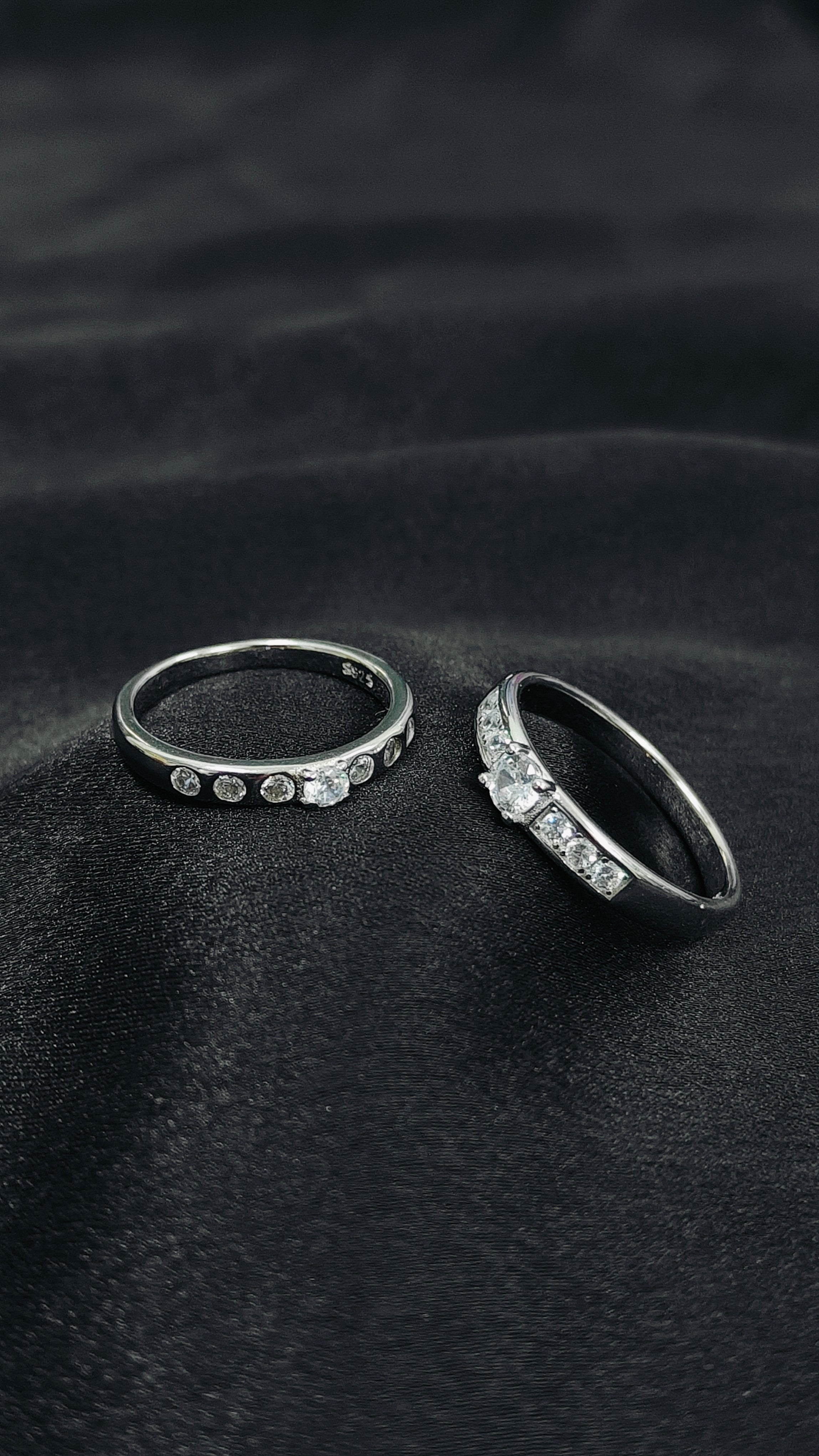 Two silver rings with gemstones on a black fabric background
