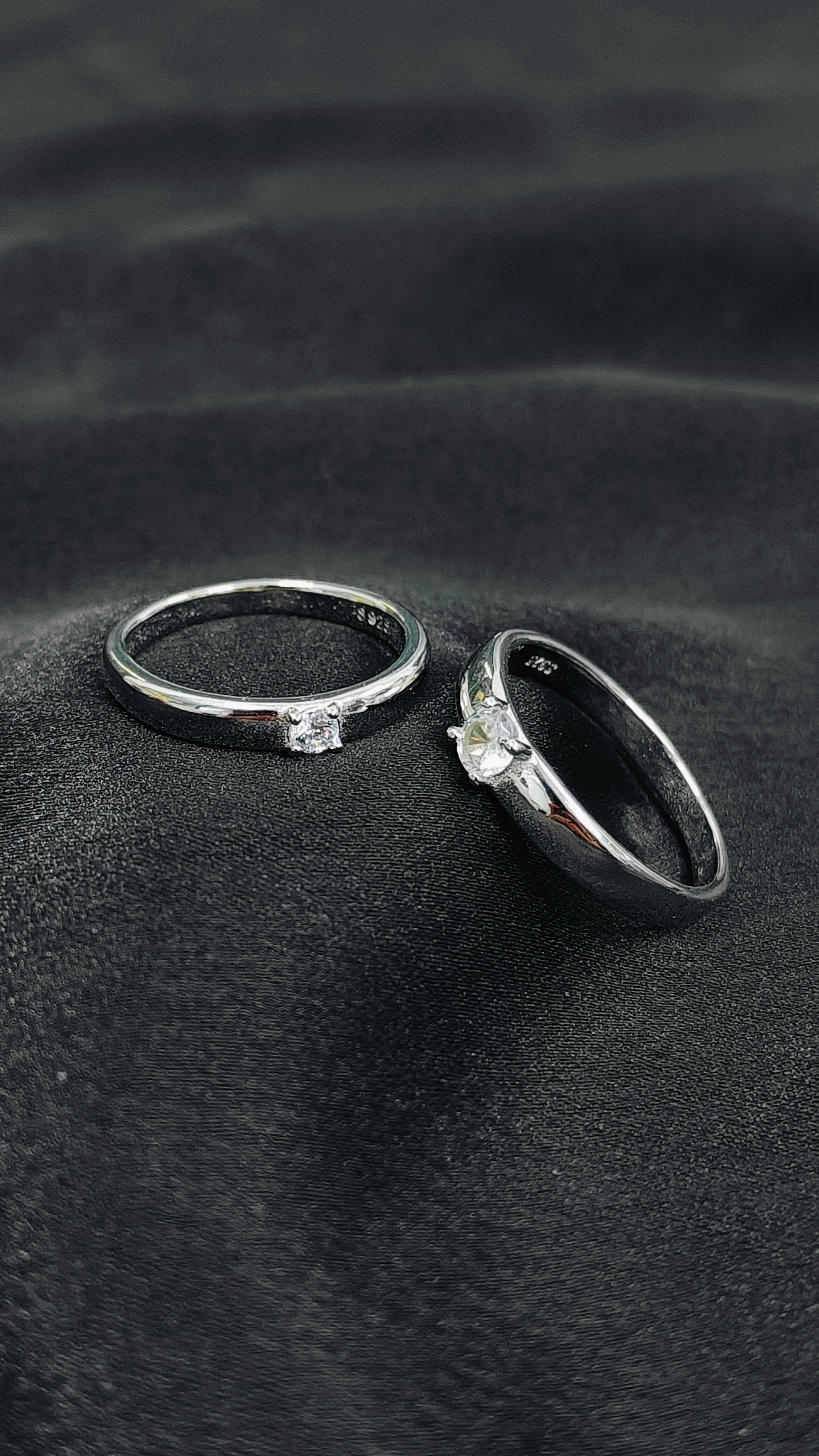 Two rings with gemstones on a dark fabric background