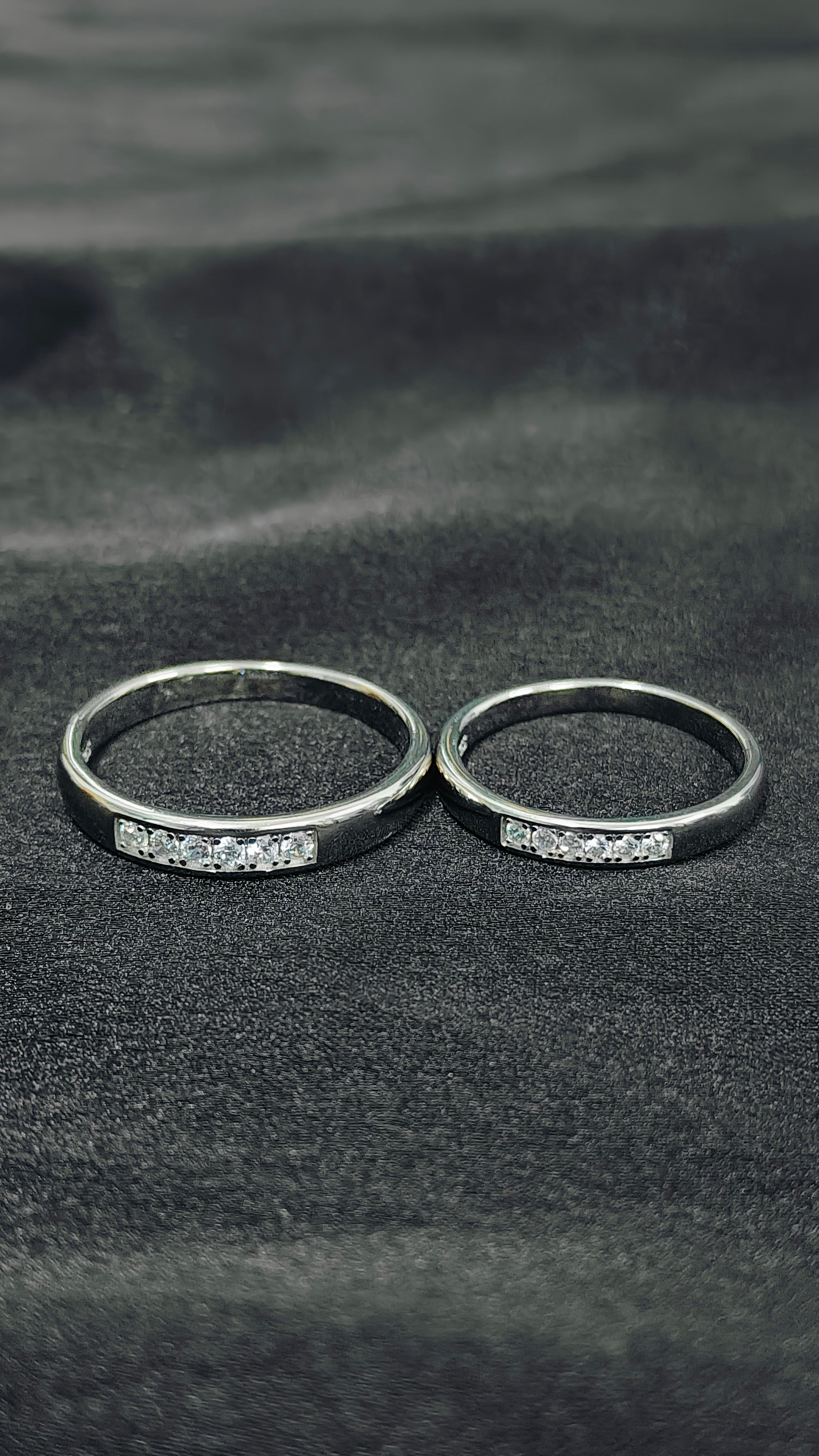 Two silver rings with gemstones on a textured black surface