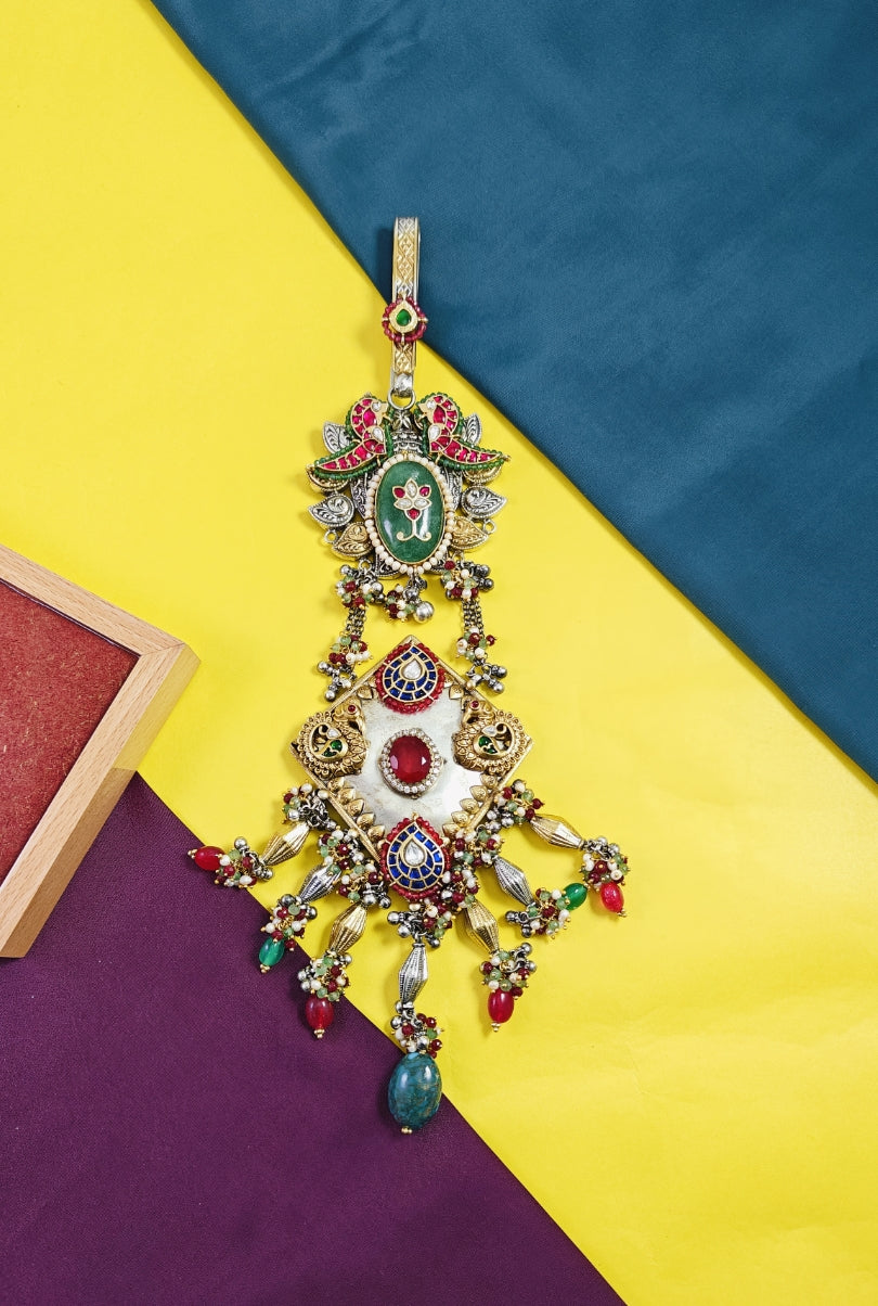 Decorative pendant with colorful gemstones on a multicolored fabric background