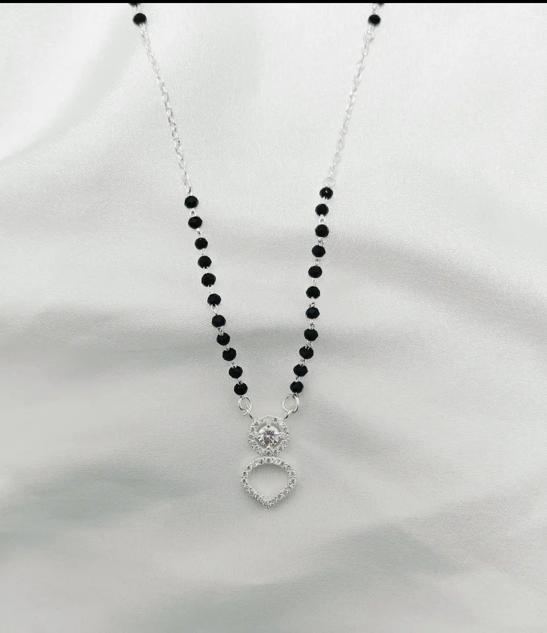 Necklace with black beads and a silver pendant on a white background
