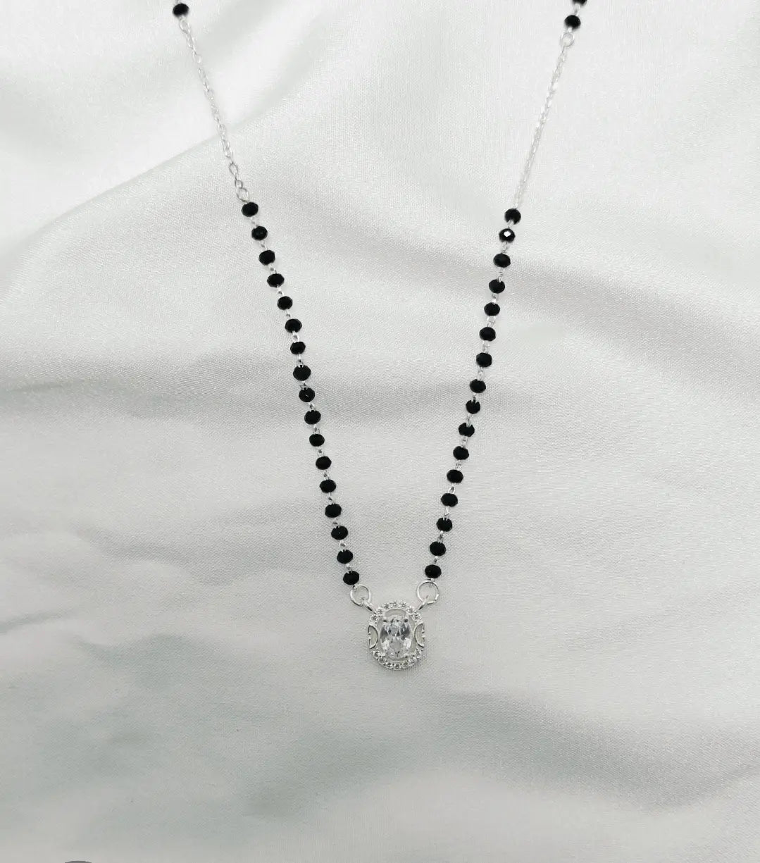Necklace with black beads and a silver clasp on a white background
