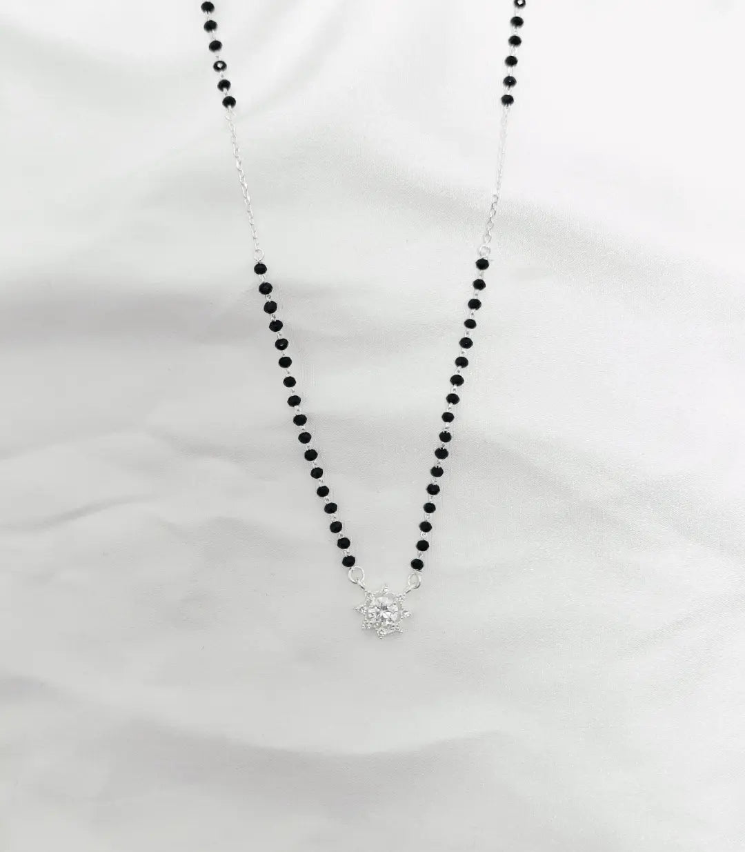 Necklace with black beads and a silver clasp on a white background
