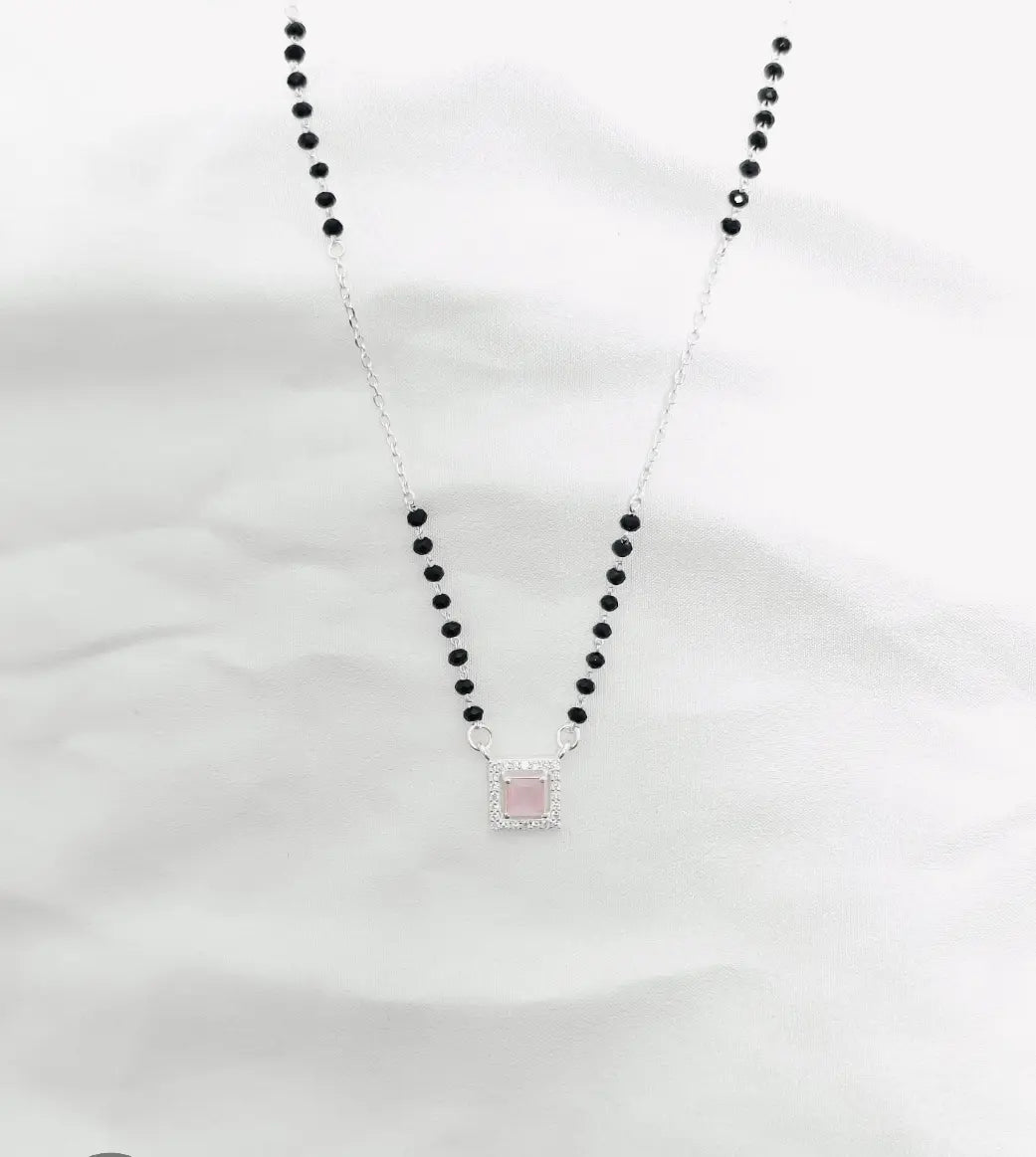 Necklace with black beads and a pink pendant on a white background