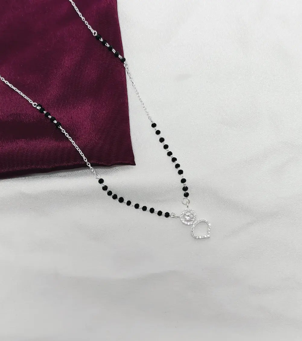 Black beaded necklace with a silver pendant on a white surface