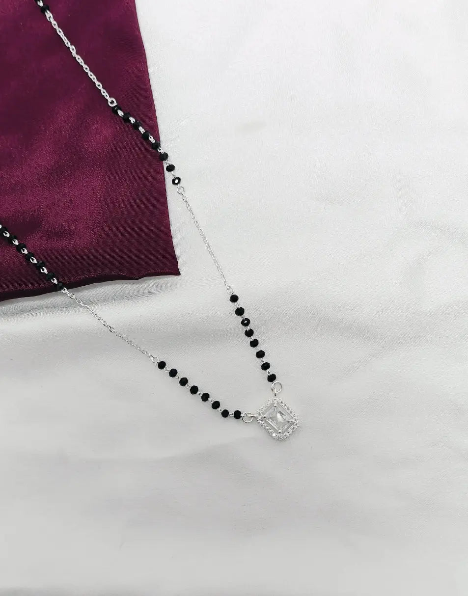 Necklace with black beads and a silver clasp on a white surface