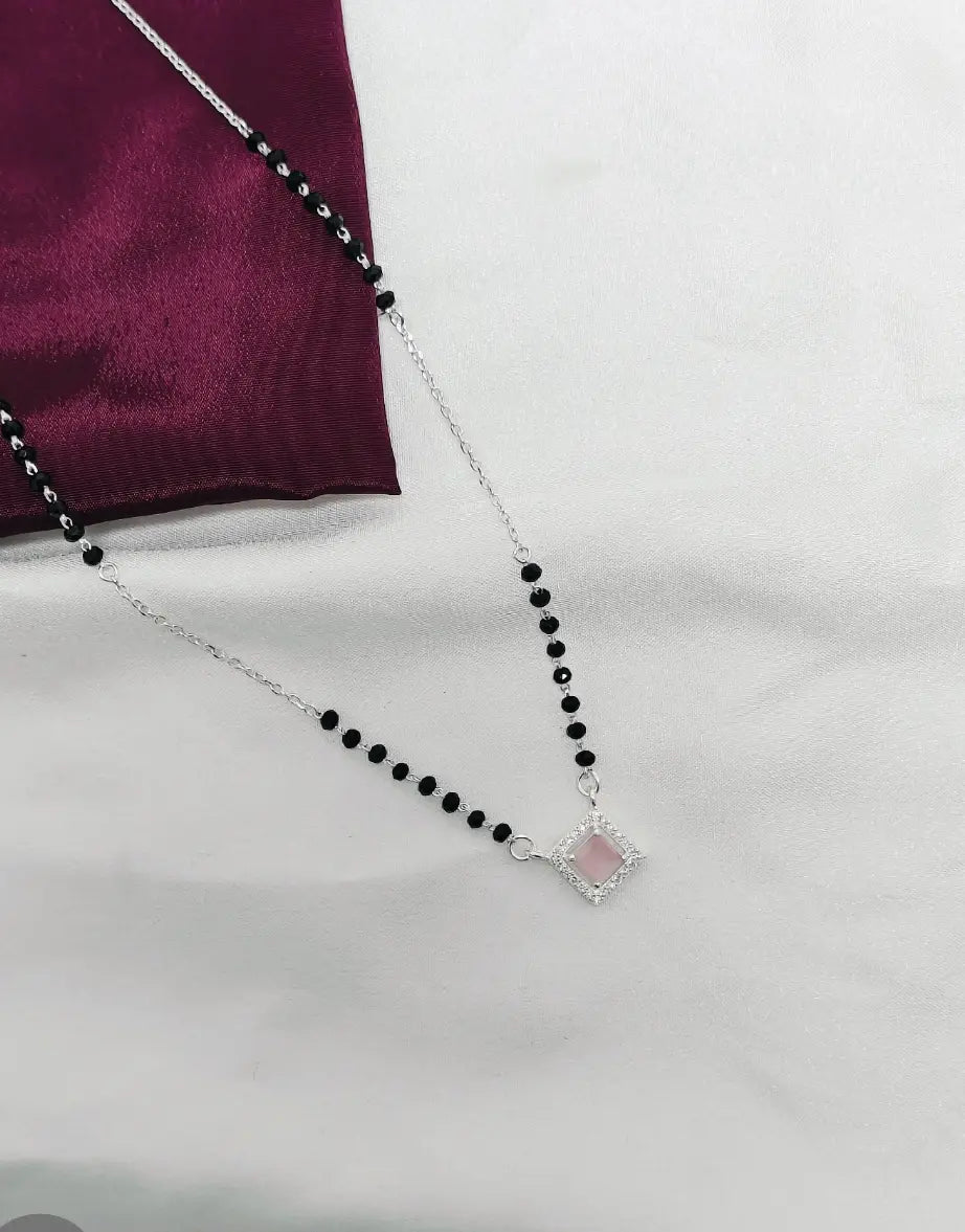 Necklace with black beads and a pink pendant on a white background