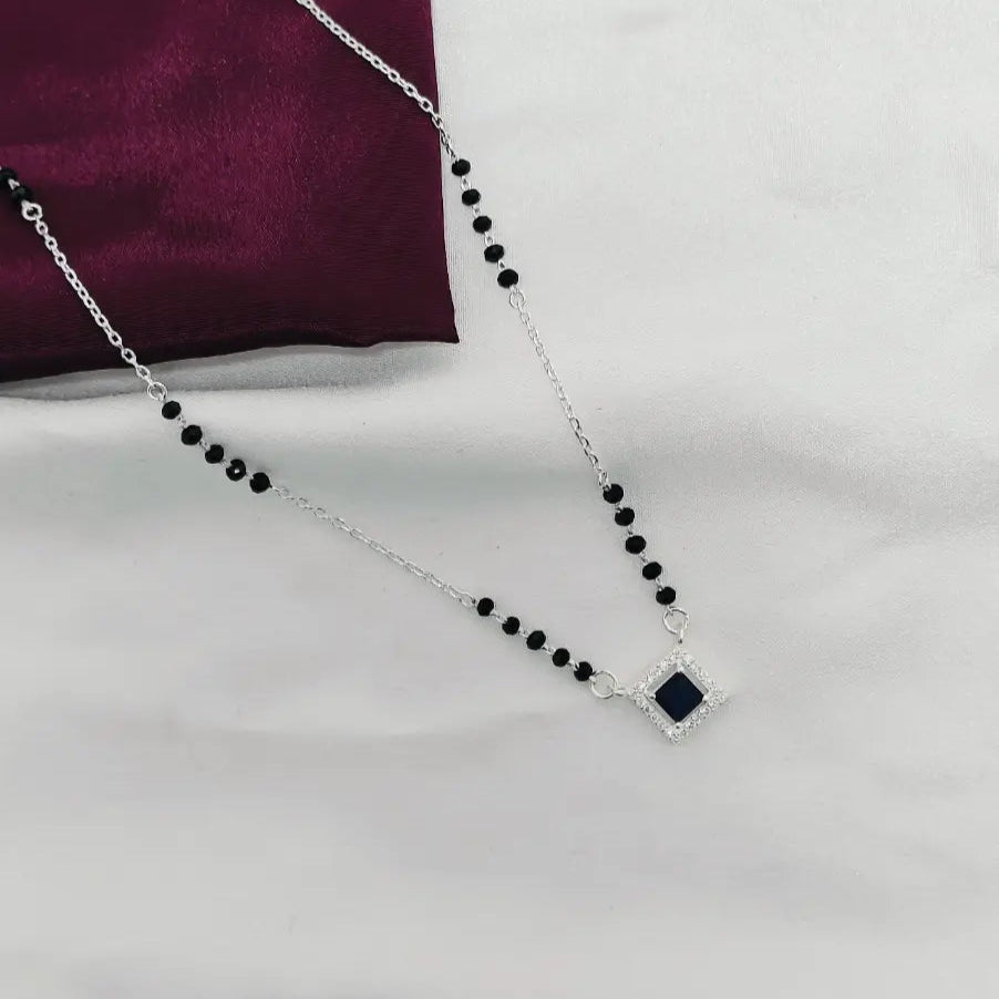 Necklace with black beads and a square pendant on a white background