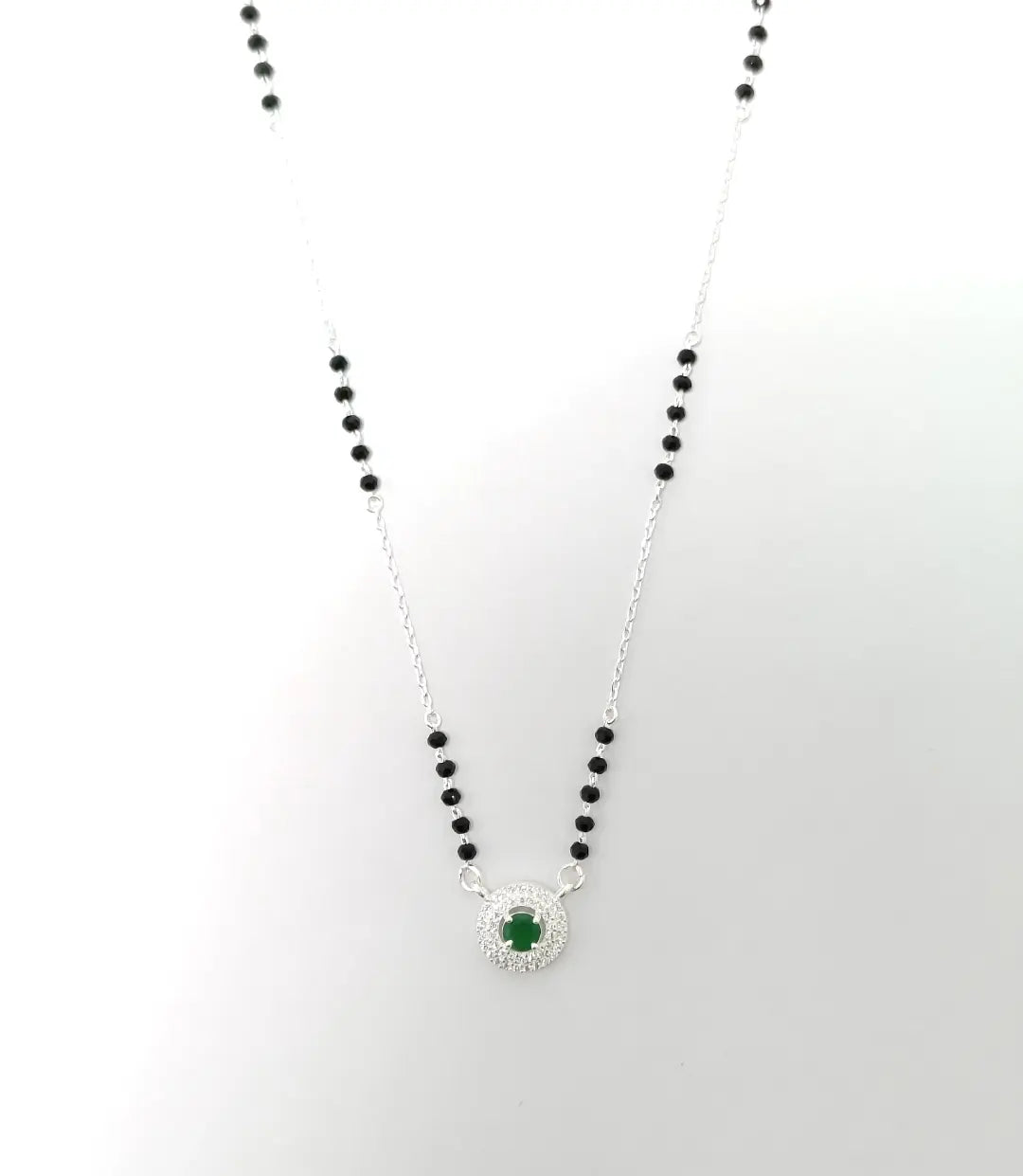 Necklace with black beads and a green gemstone pendant on a white background