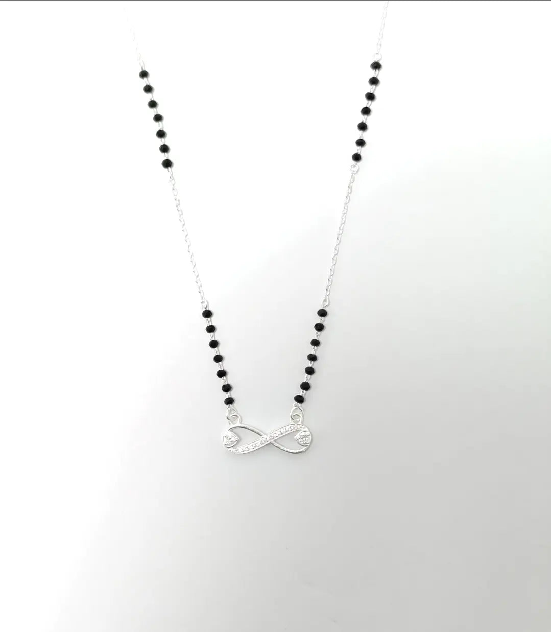 Necklace with black beads and a silver pendant on a white background