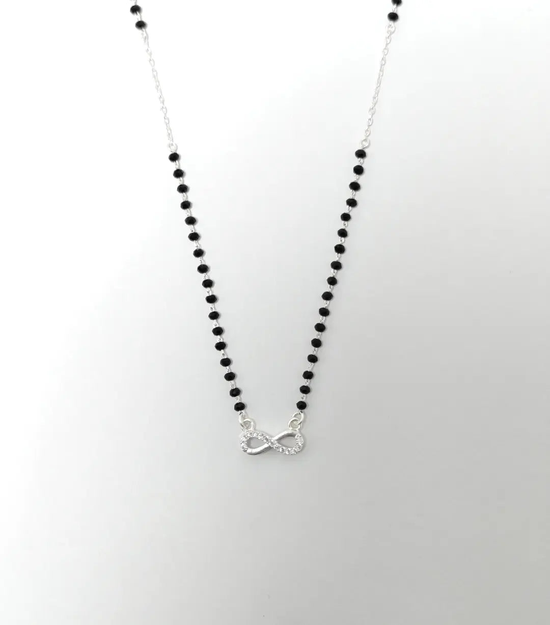 Necklace with black beads and a silver heart pendant on a white background