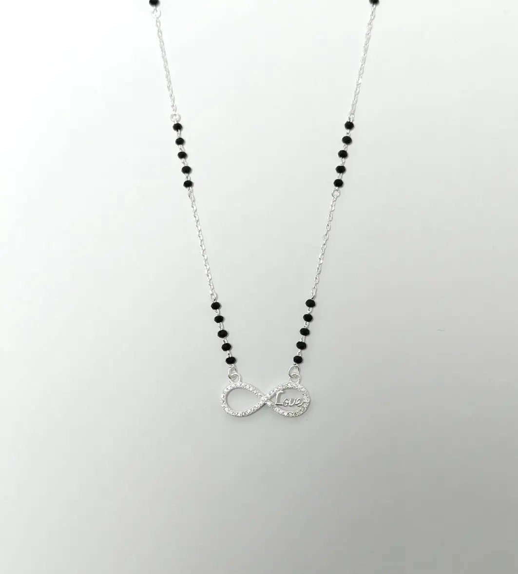 Necklace with black beads and a silver infinity symbol pendant on a light gray background