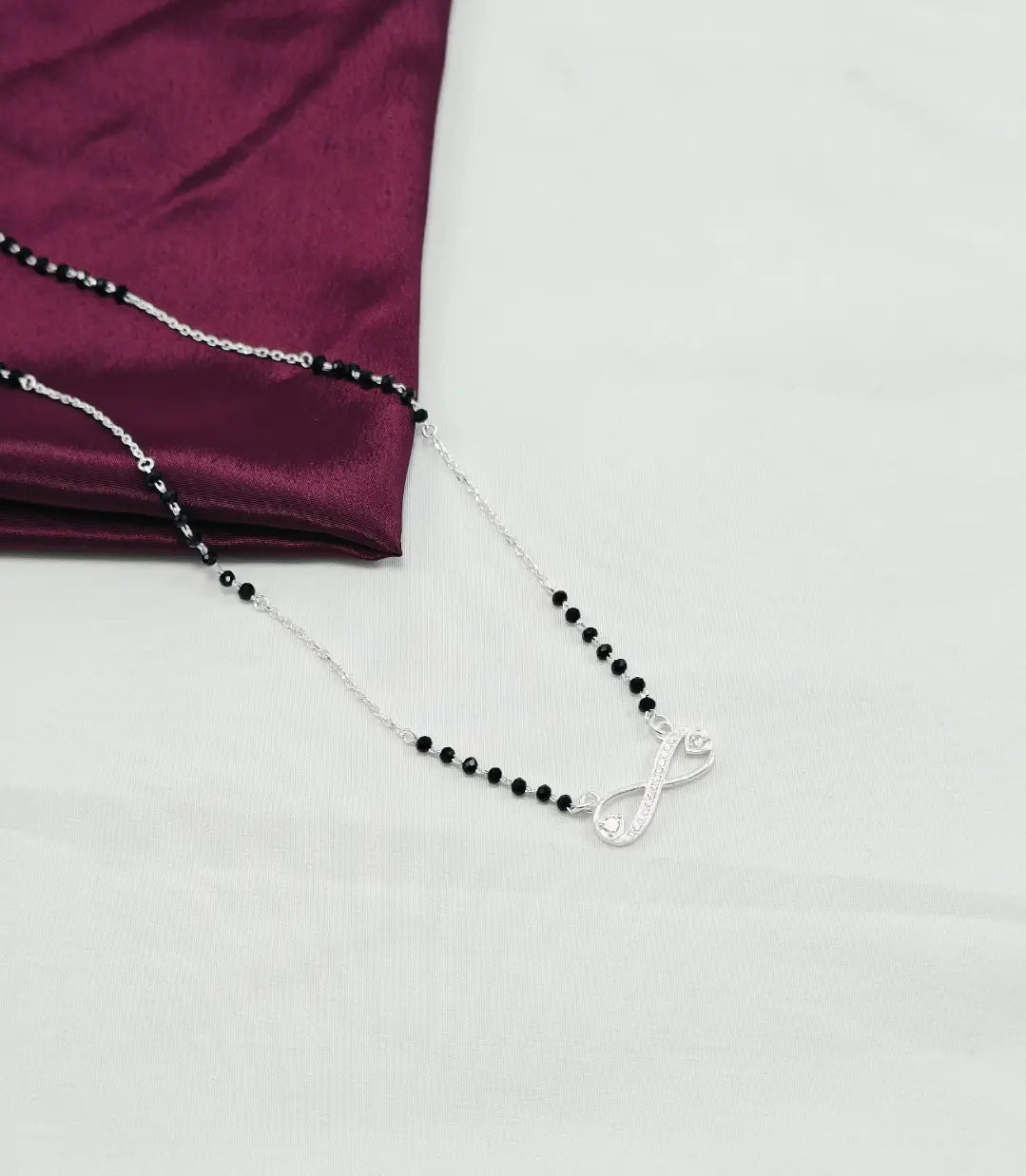 Silver necklace with black beads on a white background